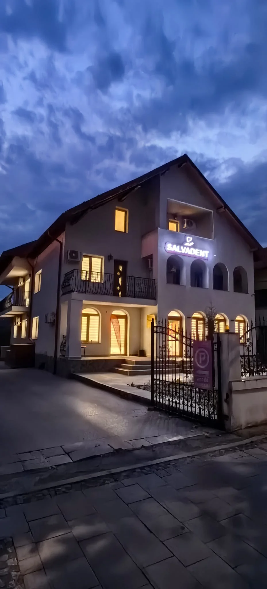 Clădirea clinicii văzută din colț, cu poarta și intrarea luminate